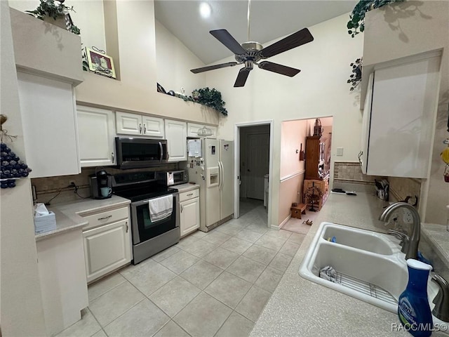 kitchen featuring stainless steel appliances, sink, tasteful backsplash, light tile patterned floors, and white cabinets