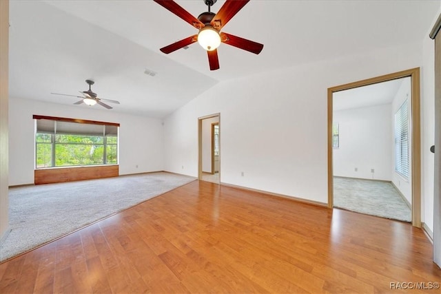 10741 W Pine Bark Ln, Crystal River, FL 34429 - spare room featuring a ceiling fan, light wood-type flooring, vaulted ceiling, and light carpet