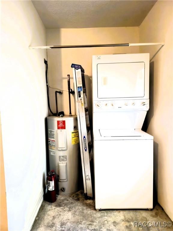 clothes washing area featuring water heater, stacked washer / drying machine, and laundry area