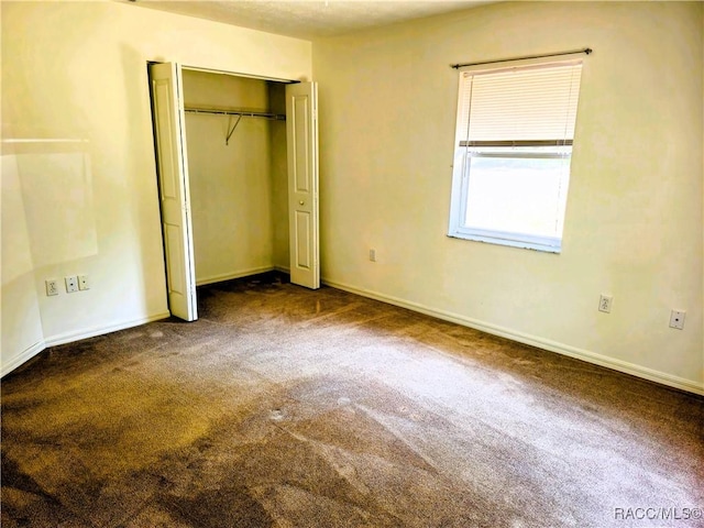 unfurnished bedroom featuring carpet floors, baseboards, and a closet
