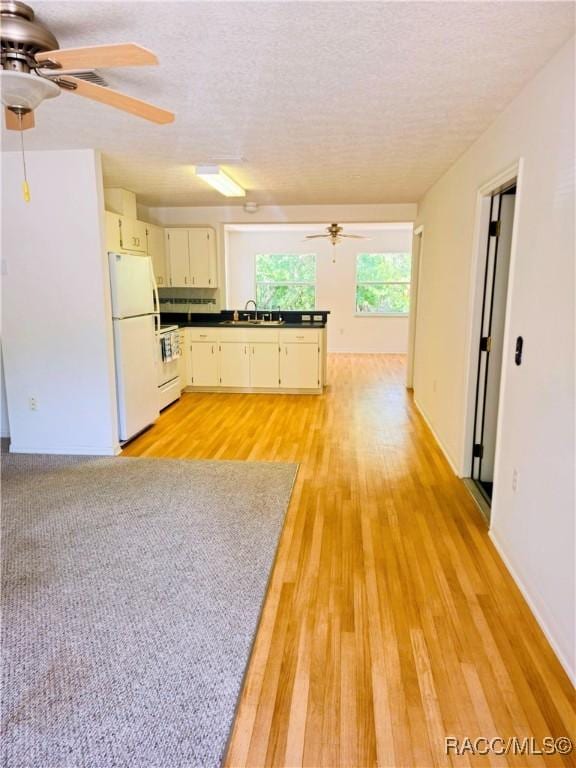 kitchen featuring a sink, dark countertops, ceiling fan, and freestanding refrigerator