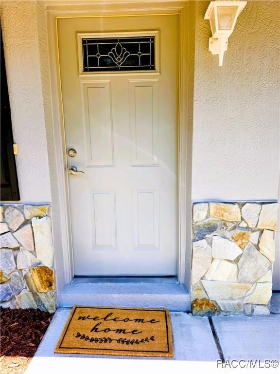 entrance to property featuring stucco siding and stone siding