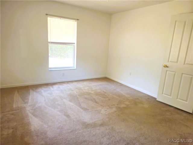 spare room featuring carpet flooring and baseboards