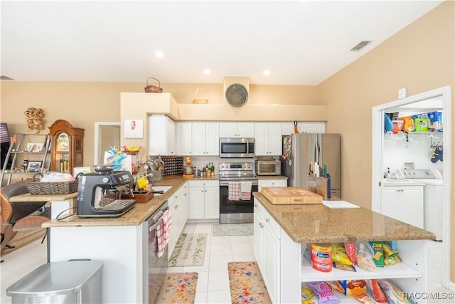 kitchen featuring visible vents, appliances with stainless steel finishes, open shelves, washing machine and dryer, and white cabinetry