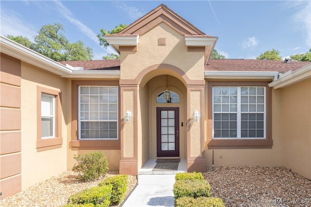property entrance featuring a shingled roof and stucco siding