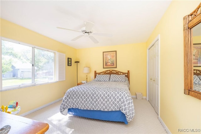 bedroom with light colored carpet, a ceiling fan, baseboards, and a closet