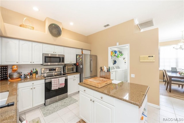 kitchen with washer and dryer, light tile patterned floors, white cabinets, backsplash, and stainless steel appliances