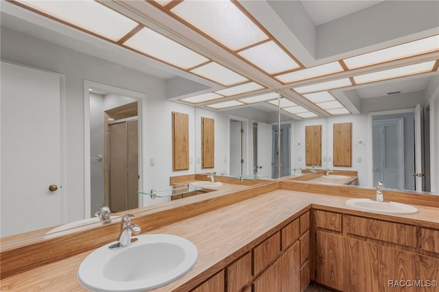 bathroom featuring double vanity, a sink, and a shower stall