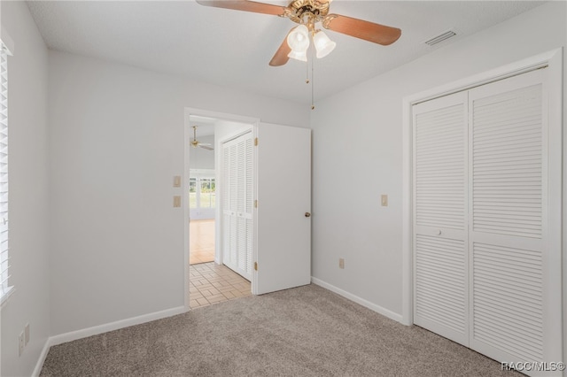 unfurnished bedroom featuring baseboards, visible vents, a ceiling fan, carpet, and a closet