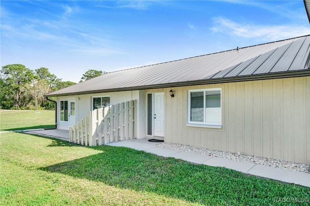 back of property featuring metal roof and a yard