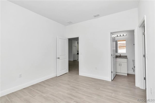 7858 N Merrimac Way, Citrus Springs, FL 34434 - unfurnished bedroom featuring light wood finished floors, baseboards, a sink, and connected bathroom
