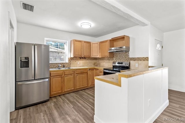 kitchen with kitchen peninsula, appliances with stainless steel finishes, decorative backsplash, light brown cabinets, and light hardwood / wood-style floors