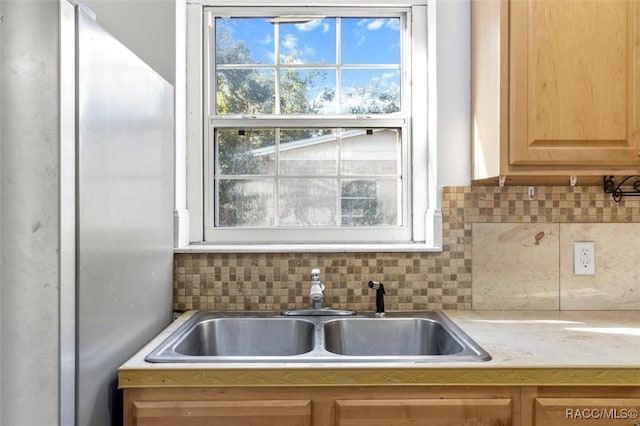 kitchen featuring stainless steel fridge, decorative backsplash, and sink