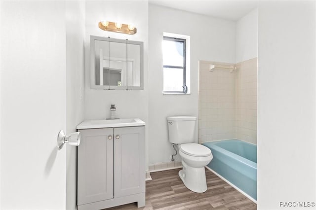 full bathroom with vanity, wood-type flooring, tiled shower / bath combo, and toilet