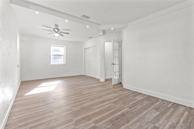 unfurnished room with beam ceiling, ceiling fan, and light wood-type flooring