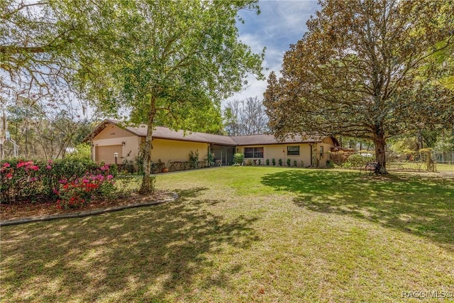 exterior space with a garage, a front lawn, and stucco siding