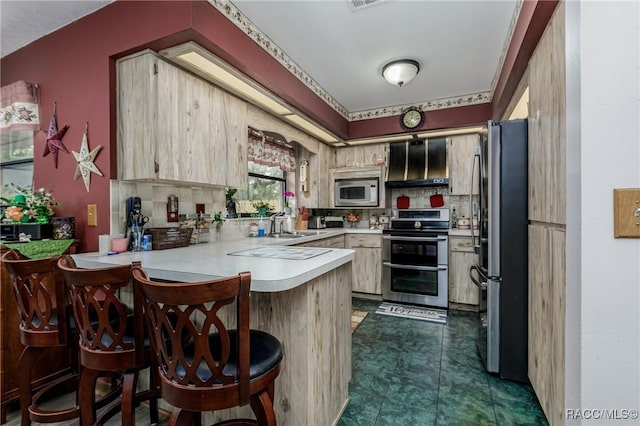 kitchen with light brown cabinets, a peninsula, a sink, light countertops, and appliances with stainless steel finishes