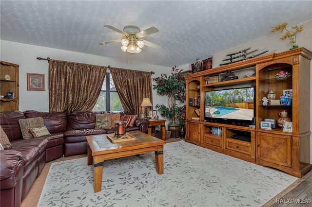 living area with a textured ceiling and a ceiling fan