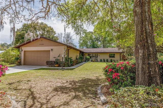 single story home with a garage, concrete driveway, a front lawn, and stucco siding