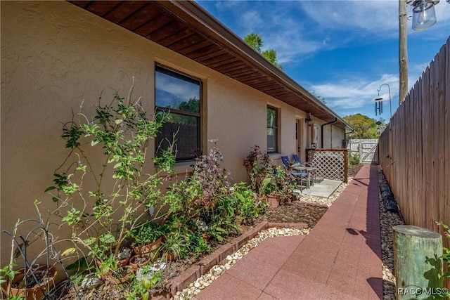 view of property exterior featuring a patio, fence, and stucco siding