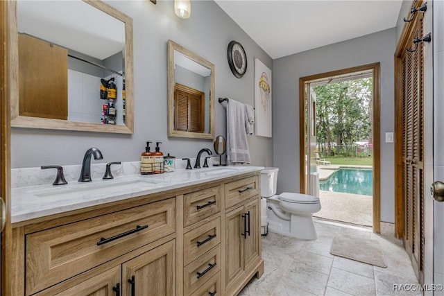 bathroom featuring double vanity, a sink, and toilet