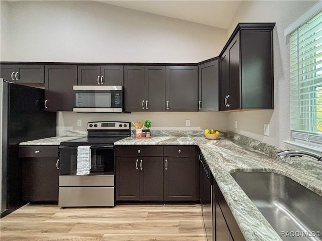 6431 SW 145th Ln, Ocala, FL 34473 - kitchen featuring appliances with stainless steel finishes, vaulted ceiling, light wood-type flooring, light stone counters, and dark brown cabinetry