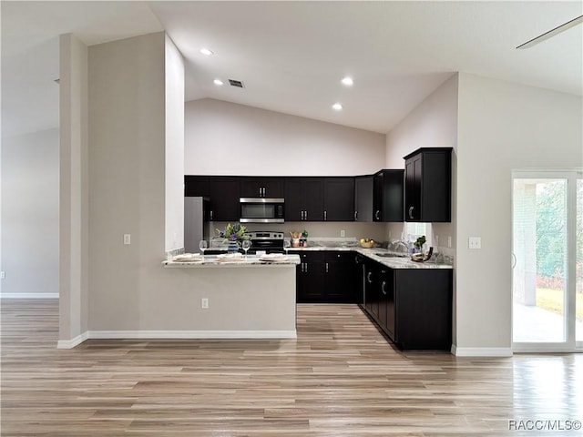 6431 SW 145th Ln, Ocala, FL 34473 - kitchen with stainless steel appliances, dark cabinets, light wood-style floors, high vaulted ceiling, and recessed lighting