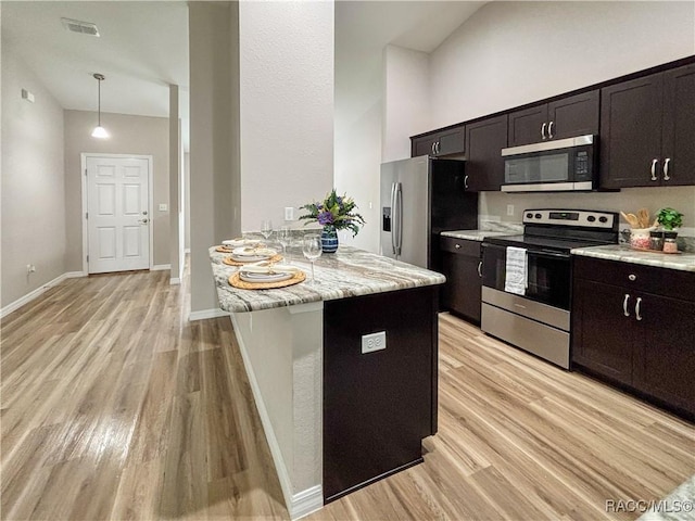 6431 SW 145th Ln, Ocala, FL 34473 - kitchen with stainless steel appliances, light wood-style flooring, a peninsula, light stone counters, and pendant lighting