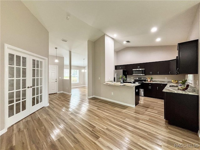 6431 SW 145th Ln, Ocala, FL 34473 - kitchen with stainless steel appliances, open floor plan, dark cabinetry, light countertops, and light wood-style flooring
