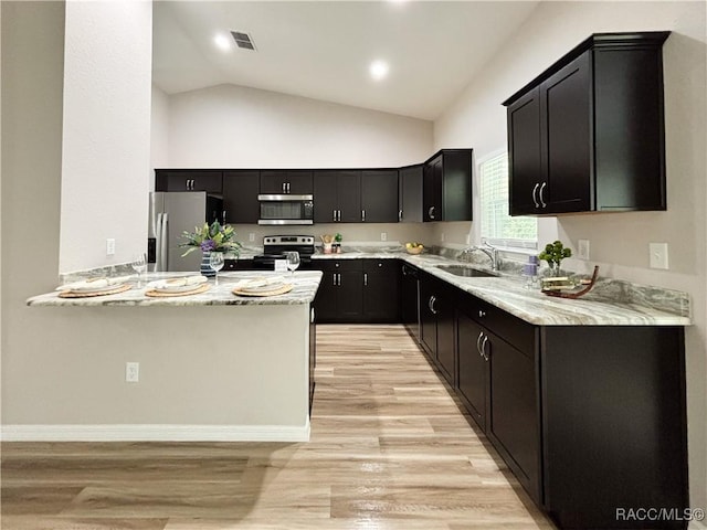 6431 SW 145th Ln, Ocala, FL 34473 - kitchen with stainless steel appliances, dark cabinetry, light wood finished floors, and vaulted ceiling