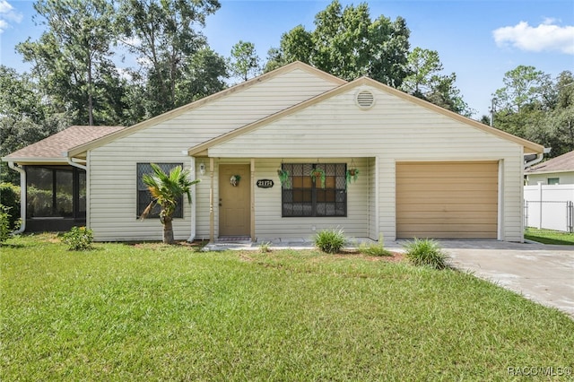 view of front facade with a front yard, fence, driveway, a sunroom, and a garage