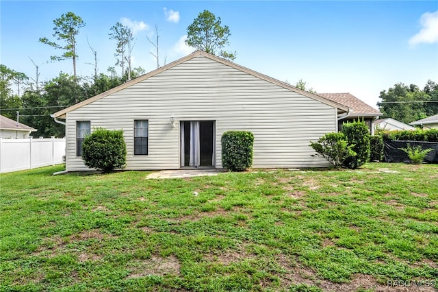 rear view of house featuring a lawn and fence