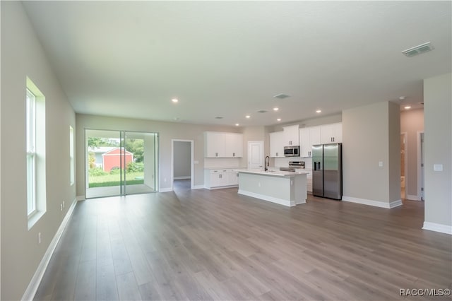 kitchen with white cabinetry, sink, an island with sink, light hardwood / wood-style floors, and appliances with stainless steel finishes