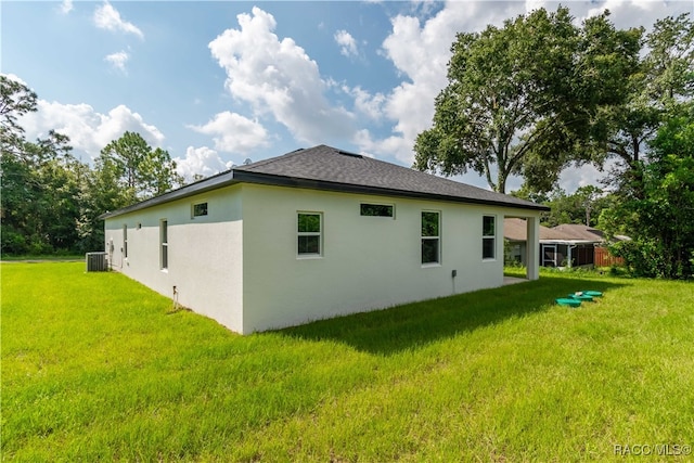 rear view of property featuring a lawn and central AC