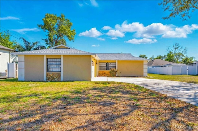 view of front of property with central AC unit, fence, a front lawn, stucco siding, and driveway