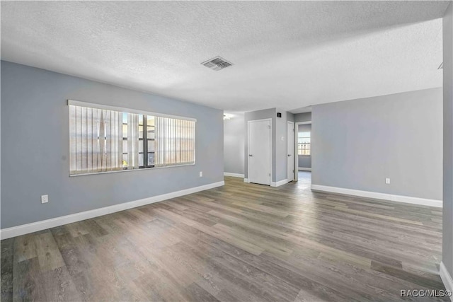 interior space featuring wood finished floors, a textured ceiling, baseboards, and visible vents