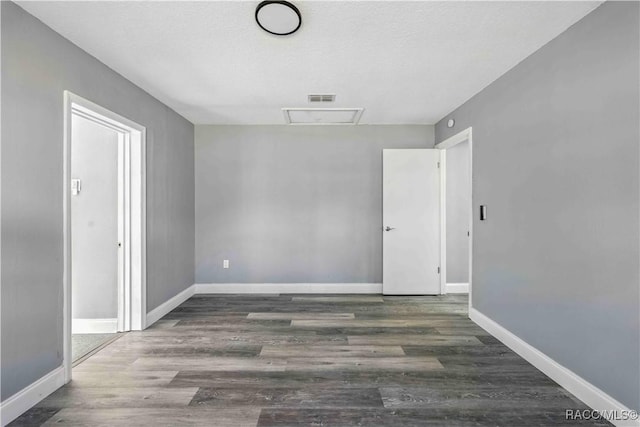 unfurnished room with attic access, baseboards, and wood finished floors