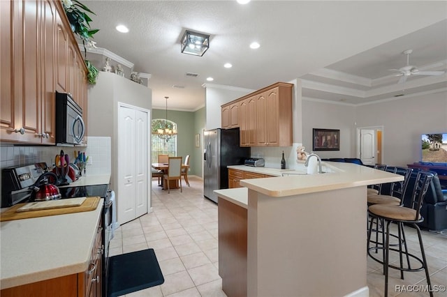 kitchen featuring a kitchen bar, kitchen peninsula, stainless steel appliances, crown molding, and ceiling fan with notable chandelier