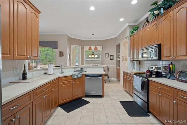 kitchen featuring appliances with stainless steel finishes, a chandelier, hanging light fixtures, ornamental molding, and sink