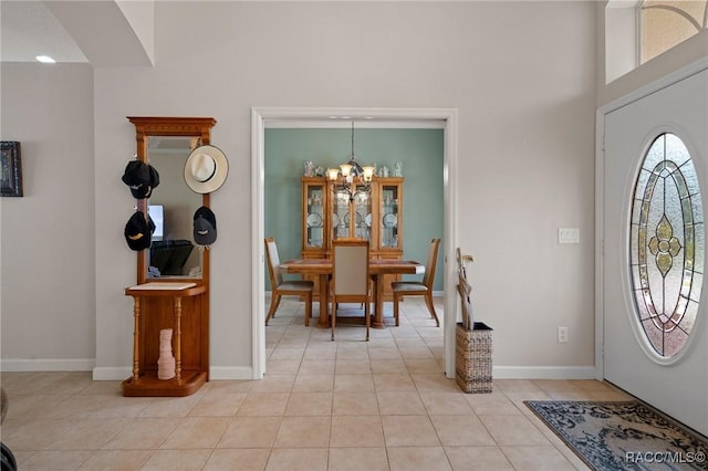 entrance foyer featuring light tile patterned flooring, a chandelier, and a towering ceiling