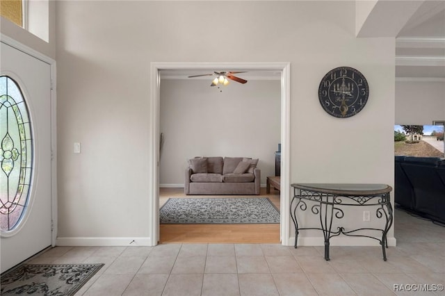 tiled foyer entrance featuring ceiling fan and crown molding