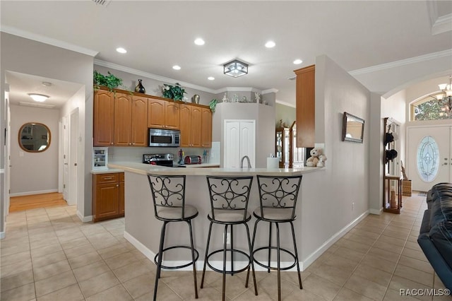 kitchen with light tile patterned floors, kitchen peninsula, crown molding, and stainless steel appliances