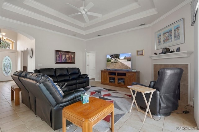 living room with light tile patterned floors, crown molding, and a tray ceiling