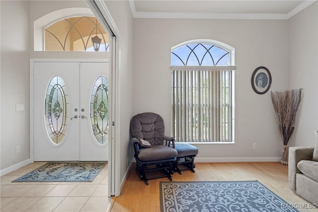 entryway featuring a wealth of natural light, ornamental molding, and light wood-type flooring