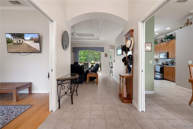 hallway with light tile patterned floors and crown molding