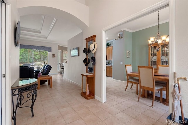 tiled entryway with a notable chandelier and crown molding