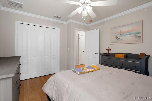 bedroom with ceiling fan, a closet, light wood-type flooring, and crown molding