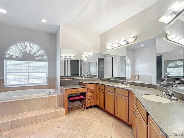 bathroom featuring vanity, tile patterned flooring, and tiled tub