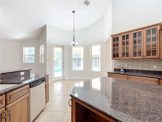 kitchen featuring backsplash, stainless steel dishwasher, brown cabinets, visible vents, and dark stone counters