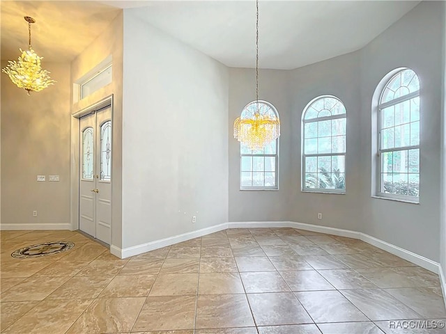 spare room featuring a healthy amount of sunlight, baseboards, and a chandelier